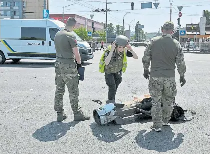  ?? AFP ?? En plena calle. Expertos ucranianos revisan restos de un misil caído entre los automóvile­s de la capital.