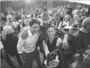  ?? CP PHOTO ?? Prime Minister Justin Trudeau poses for a selfie with a woman and man at a Canada Day barbecue in Dawson City, Yukon, on Sunday.