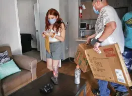  ?? Bob Owen / Staff photograph­er ?? Brianna Rubio of Brownsvill­e checks messages as her dad, Adrian Rubio, helps her move into University Oaks, an on-campus apartment complex at UTSA.