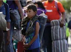  ?? Associated Press ?? ■ Young Honduran migrant Daniel Gamez waits with his family in a line for a meal after arriving with the Central America migrant caravan Thursday in Tijuana, Mexico. Members of a migrant caravan started to meet some local resistance as they continued to arrive by the hundreds in the Mexican border city of Tijuana, where a group of residents clashed with migrants camped out by the U.S. border fence.