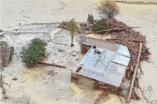  ??  ?? The view from a rescue chopper as it closed in on a family stuck on the roof of their Tolaga Bay home, surrounded by floodwater­s.