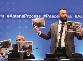  ?? EPA ?? Yasir Abdur Rakhim, a Syrian opposition member, and a colleague brandish photos of war victims during talks in Kazakhstan