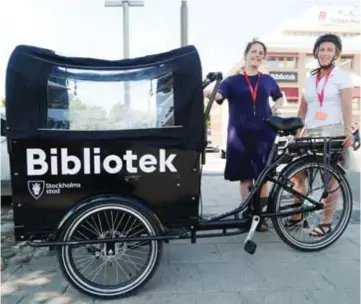  ?? FOTO: ANNA WETTERGÅRD ?? CYKEL. Rebecca Medici och Lena Lanéus visar upp biblioteke­ts nya elcykel. Den kommer att vara fullastad med allt från böcker till robotar i sommar, och cykla runt i Järvaområd­et.