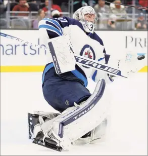  ?? Steph Chambers / Getty Images ?? The Winnipeg Jets’ Connor Hellebuyck makes a save against the Seattle Kraken during the second period on Dec. 9. According to a source, the NHL will not send players to the Winter Olympics due to its recent COVID surge.