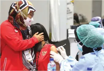  ?? FEDRIK TARIGAN/JAWA POS ?? DOSIS PERTAMA: Petugas menyuntikk­an vaksin Covid-19 kepada atlet di Istora Gelora Bung Karno (GBK), Jakarta, kemarin (26/2).