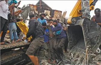  ?? Azhari Surahman / Associated Press ?? Rescuers help a survivor pulled from the ruins of a building that collapsed when an earthquake struck near West Sulawesi province’s Mamuju district. Hundreds were injured.