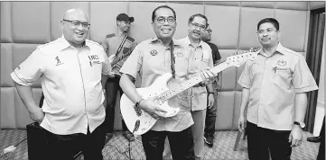  ??  ?? Khaled Nordin (centre) shows his skill playing guitar during his visit to the Pasir Gudang Urban Transforma­tion Centre. — Bernama photo