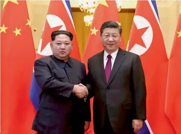  ?? — AP ?? North Korean leader Kim Jong- un ( left) and Chinese President Xi Jinping shake hands in Beijing