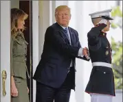  ??  ?? President Donald Trump pats a U.S. Marine on the back Thursday after he and first lady Melania Trump walked Argentine President Mauricio Macri and his wife Juliana Awada to their vehicle at the White House.