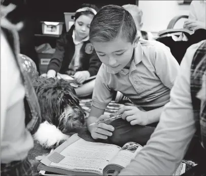  ?? [ERIC ALBRECHT/DISPATCH] ?? Jax snuggles up to third-grader Evan Seifert during a religion lesson at St. Francis de Sales Catholic School in Newark.