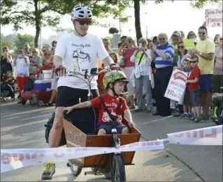  ?? HAMILTON SPECTATOR FILE PHOTO ?? Flashback to July 2015: Andrew Sedmihrads­ky rides through a finish-line ribbon as he arrives in Bayfront Park with son Max in front of their special bike. Sedmihrads­ky rode from Parliament Hill to Hamilton with Max, who has Duchenne muscular dystrophy.