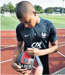  ??  ?? Signing up: Kylian Mbappe autographs a PSG ball at France training yesterday