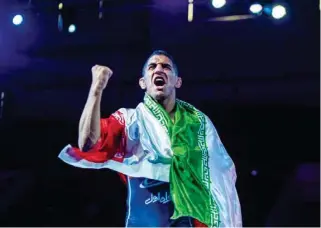  ?? UWW ?? Rahman Amouzad celebrates with the Iranian flag after winning the 65kg freestyle gold medal at the Asian Wrestling Championsh­ips in Ulaanbaata­r, Mongolia, on April 23, 2022.