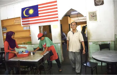  ??  ?? Tan (right) manages his coffee shop at Jalan Ampang Tinggi. — Bernama photos