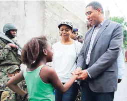  ?? FILE ?? Prime Minister Andrew Holness (right) greets a young resident inside the first zone of special operations in Mount Salem, St James, recently. Looking on is Attorney General and Member of Parliament for West Central St James Marlene Malahoo Forte...