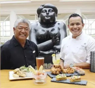  ?? The Maui News / CARLA TRACY photo ?? Longtime Botero Lounge mixologist Mich Domingo (left) and Grand Wailea Executive Sous Chef Jorge Gonzalez hang out at a high-top table with new menu items near one of several famous sculptures by Ferdinand Botero, after whom the bar is named.