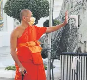  ?? VARUTH HIRUNYATHE­B ?? A monk raises his palm for a temperatur­e check at Wat Pho in Bangkok.