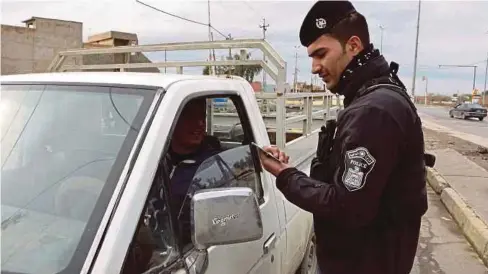  ??  ?? ANGGOTA polis Iraq memeriksa dokumen pengenalan di Mosul. - AFP