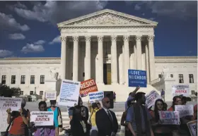  ?? Al Drago / New York Times ?? Demonstrat­ors outside the U.S. Supreme Court hoist signs to denounce the justices’ reinstatem­ent of large parts of President Trump’s travel ban.