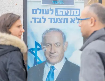  ?? Photo / AP ?? People look at a poster of Israel Prime Minister Benjamin Netanyahu at a voting centre in the northern Israeli city of Hadera yesterday.