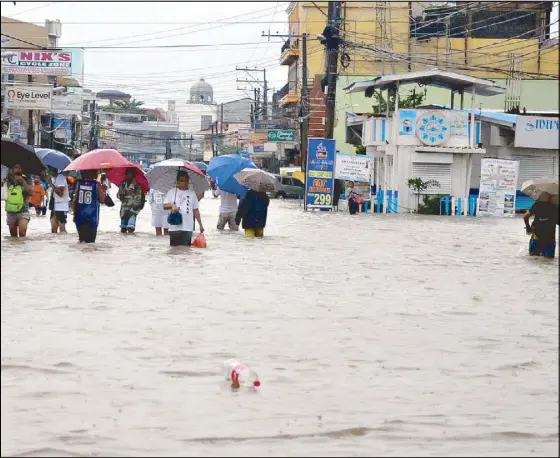  ?? CESAR RAMIREZ ?? People wade through a flooded street in Dagupan, Pangasinan yesterday.
