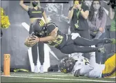  ?? ANDY NELSON — THE ASSOCIATED PRESS ?? Oregon running back Travis Dye (26) dives into the end zone over Cal safety Daniel Scott (32) during the second quarter on Friday in Eugene, Ore.