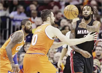  ??  ?? CLEVELAND: Miami Heat’s Derrick Williams, right, passes around Cleveland Cavaliers’ Kyrie Irving and Kevin Love in the first half of an NBA basketball game Friday, in Cleveland. — AP