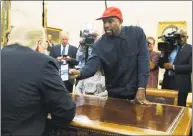  ?? Evan Vucci / Associated Press ?? Rapper Kanye West shows President Donald Trump a photo during a meeting at the White House on Thursday.