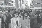  ?? JIJI PRESS/AFP VIA GETTY IMAGES ?? People in Tokyo take part in a moment of silence, which was observed nationwide at 2:46 p.m., the moment the earthquake struck on March 11, 2011.