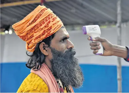  ?? REUTERS ?? A Sadhu or a Hindu holy man gets his temperatur­e measured at a base camp where pilgrims gather before heading for an annual trip to Sagar Island for the one-day festival of “Makar Sankranti” in Kolkata, India on Friday.