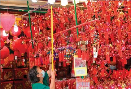  ?? AFP PHOTO ?? Chinatown district in Singapore on Monday, Jan. 10, 2022.
A vendor hangs decorative ornaments for sale for the upcoming Lunar New Year of the Tiger in the