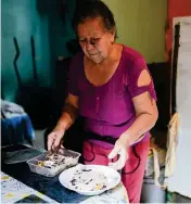  ?? ARIANA CUBILLOS AP ?? Maybel Sequera divides a donated plate of noodles and beans to share with her husband at their home in the low-income neighborho­od of La Vega in Caracas. Their lunch was a gift from a nonprofit organizati­on, as the seamstress and retired driver cannot afford to feed themselves on their monthly pensions and have to rely on donations for food, medicines and clothing.