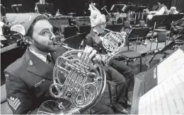  ??  ?? French horn players Petty Officer 2nd class Brian Hall and Petty Officer 2nd class Allison Zaichkowsk­i warm up before the show.