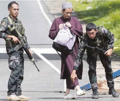  ?? —BULLIT MARQUEZ/AP ?? CHECKPOINT Soldiers frisk a Muslim man at a checkpoint near Marawi City. Authoritie­s have been verifying the identities of people in key cities in Mindanao after President Duterte proclaimed martial law on the island in the wake of clashes between...