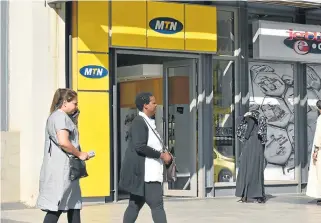  ?? /Freddy Mavunda ?? Increasing challenges: People walk past an MTN Store in Rosebank. The group is facing a number of headwinds in its key markets, SA and Nigeria.