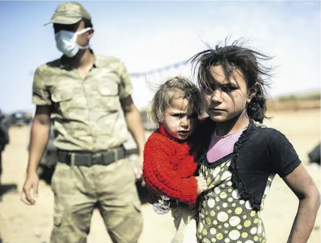  ?? BULENT KILIC / AFP / Get
y Images ?? A Syrian Kurdish girl holds her sister in the southeaste­rn town of Suruc in Turkey’s Sanliurfa province after they crossed the border Thursday from Syria.
Turkey’s parliament Thursday approved a resolution calling for the NATO member to join the...