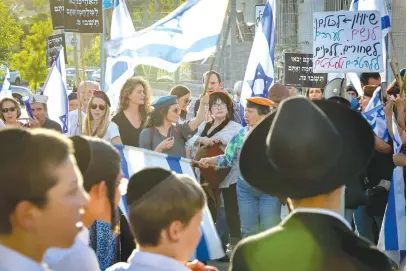  ?? (Noam Revkin Fenton/Flash90) ?? PROTESTERS STAND across from haredi boys in front of Kol Torah Yeshiva in Jerusalem, earlier this month.