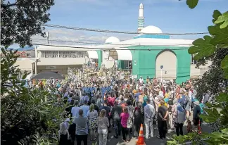  ??  ?? The crowd that gathered outside the Wellington Islamic Community mosque yesterday.
Below: People link arms around the venue to protect those praying inside.