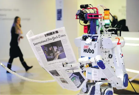  ?? FABRICE COFFRINI/AFP ?? A robot holds a newspaper during a demonstrat­ion of reading comprehens­ion during the World Economic Forum annual meeting in Davos Switzerlan­d. Devices using artificial intelligen­ce are already doing things such as paralegal work and writing formulaic...