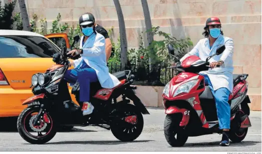  ?? ERNESTO MASTRASCUS­A / EFE ?? Dos sanitarios viajan en sus motociclet­as por una calle de La Habana.