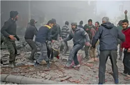  ?? — AFP ?? Syrian rescuers evacuate badly injured people following regime strikes on the besieged rebel- held enclave of Kafr Batna near Damascus on Tuesday.