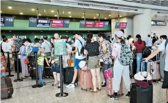  ??  ?? Passengers stranded by Lekima check in at Hongqiao airport yesterday. — IC