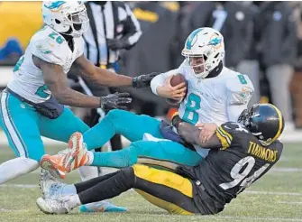  ?? JIM RASSOL/STAFF PHOTOGRAPH­ER ?? Miami Dolphins quarterbac­k Matt Moore gets sacked by Pittsburgh Steelers inside linebacker Lawrence Timmons. Moore was sacked five times during the game, fumbling the ball twice.