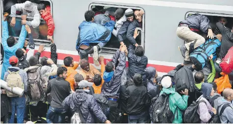  ?? JEFF J MITCHELL/Getty Images ?? Migrants desperatel­y try to board a train heading for Zagreb from Tovarnik station early Monday in Tovarnik, Croatia.