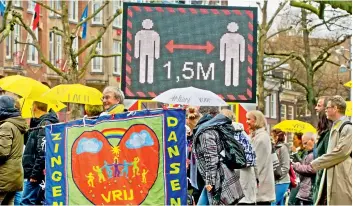  ?? AP ?? Protesters pass a digital billboard urging people to respect the 1.5 metre social distancing guidelines during a demonstrat­ion against Coronaviru­s related restrictio­ns in Amsterdam, Netherland­s, on Sunday. —