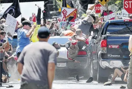  ?? Ryan M. Kelly Daily Progress ?? A CAR PLOWS into a group of anti-racists, killing one. Two Virginia troopers monitoring events also died when their helicopter crashed.