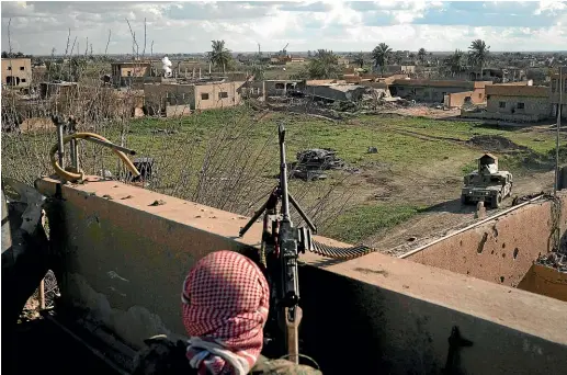  ?? AP ?? A Syrian Democratic Forces fighter looks out over the last piece of land held by Islamic State, from the roof of a building in Baghouz, Syria. Hundreds of Isis militants trapped in the pocket are refusing to surrender and trying to negotiate an exit.