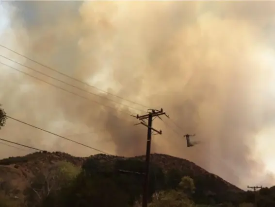  ?? (AP) ?? A helicopter drops water on a wildfire burning in Santa Clarita, California