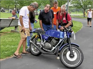  ?? Photos for the Gazette by PHIL HEIL ?? A group of aficionado­s look over a race modified early RT-350 Yamaha at the second annual Vintage Motorcycle Daze Aug. 4 at Wentz Run Park.