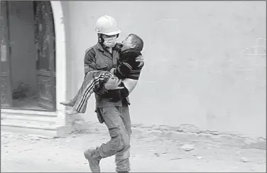  ?? AP ?? A member of the Syrian civil defense group known as the White Helmets carries a boy injured during Wednesday’s airstrikes in Ghouta in this photo provided by the rescue group.